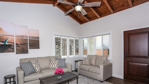 A living room with two sofas, a coffee table, and a ceiling fan.