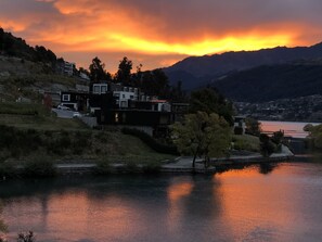 Vista de un lago con casas modernas, un lago tranquilo y montañas al fondo.