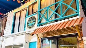 A two-story building with a signboard advertising available rooms. - AKBAL Holbox (Isla Holbox)