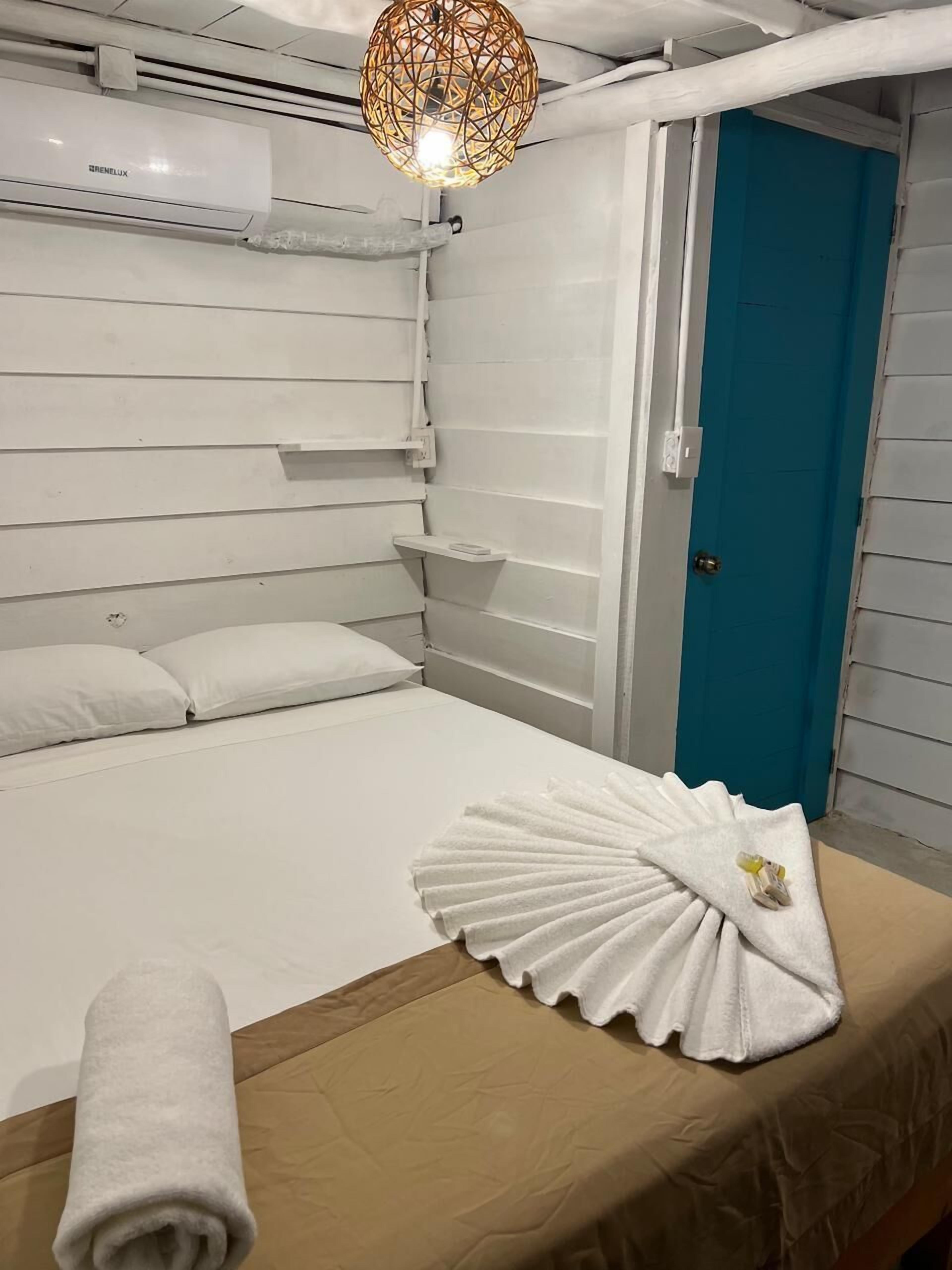 Een hotelkamer met een bed, een handdoek, een plank en een deur.