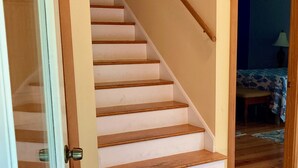 Una escalera con escalones de madera y un felpudo verde al final.