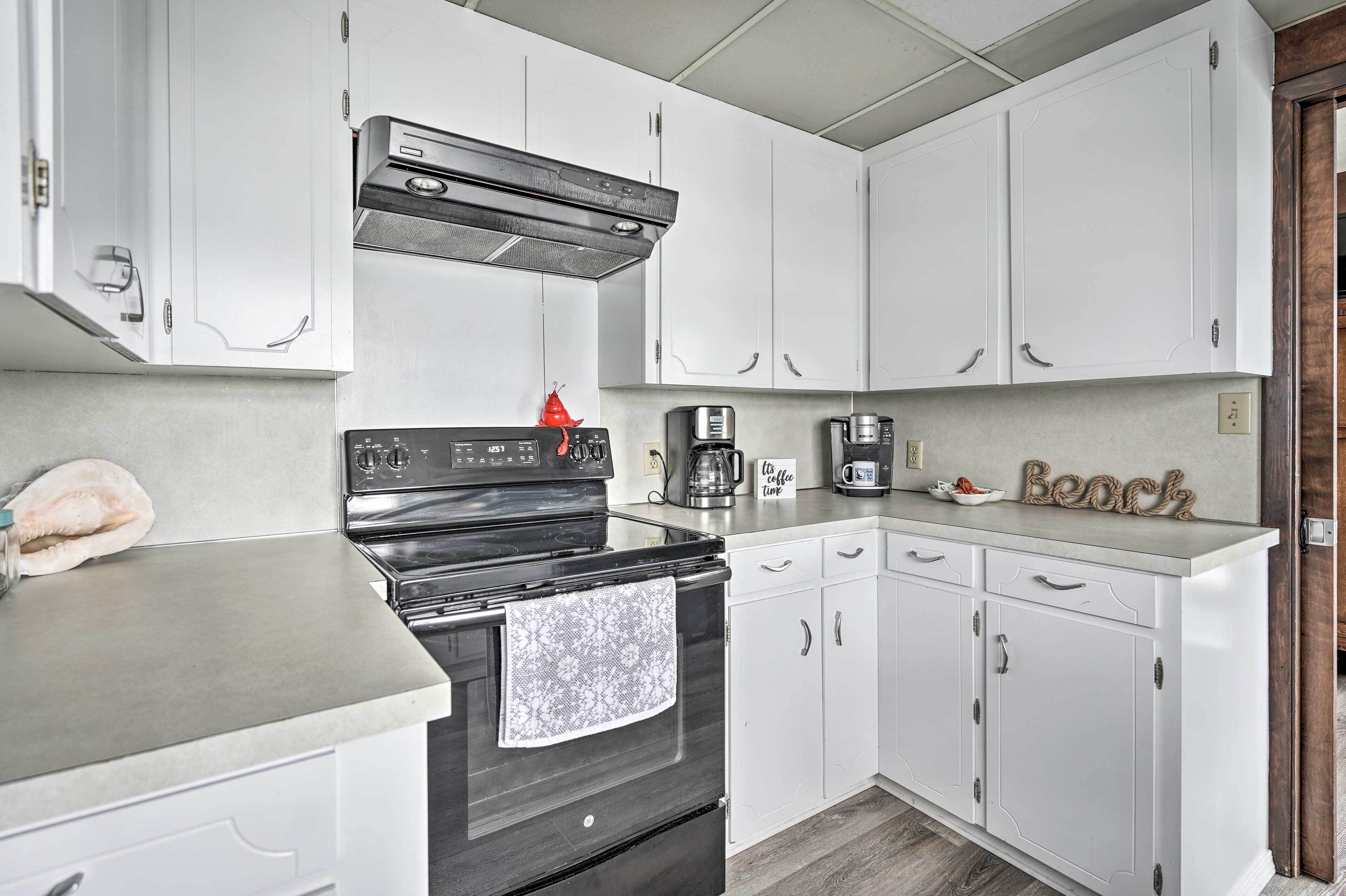 A kitchen with white cabinets, a black stove, and a coffee maker.