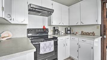 A kitchen with white cabinets, a black stove, and a coffee maker.