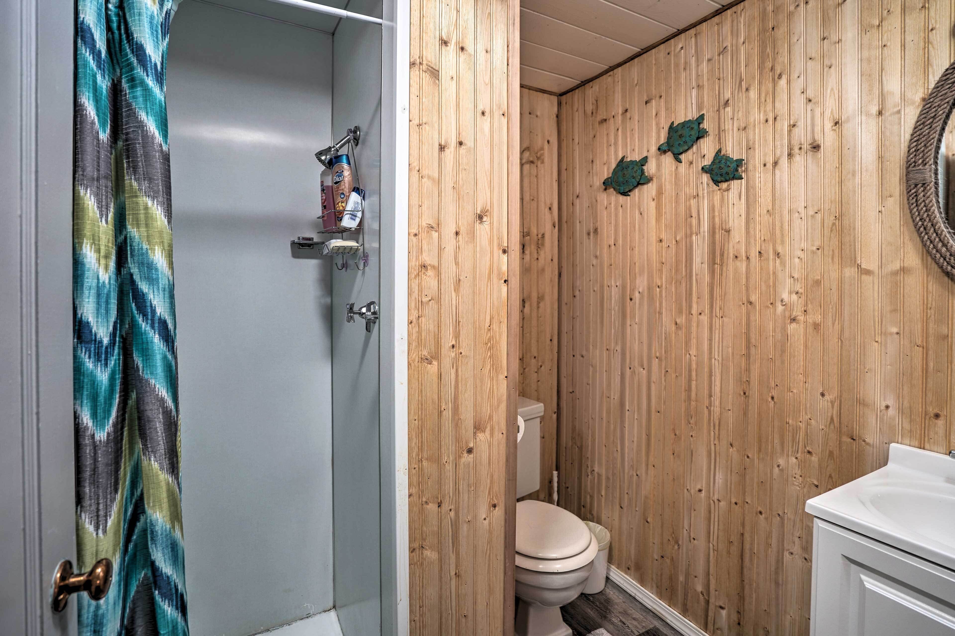Et badeværelse med trævæg, toilet og bruseområde.
