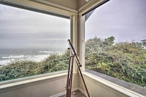 Ein Teleskop steht an einem Fenster mit Blick auf den Ozean.