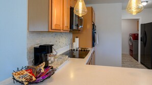 A modern kitchen with wooden cabinets, a black stove, and a coffee maker. - The Bright Home (Odessa)