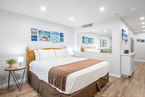 Une chambre d’hôtel avec un lit, une table de chevet, une lampe, une plante en pot et des œuvres d’art mural.