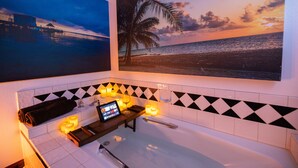Ein Badezimmer mit Badewanne, Handtuchhalter und Ablagefläche mit Kerzen und einem Tablet.