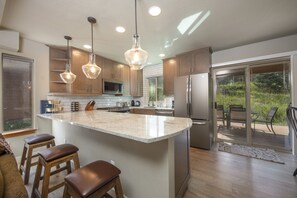 Een moderne keuken met een groot eiland, roestvrijstalen apparatuur en houten kasten.