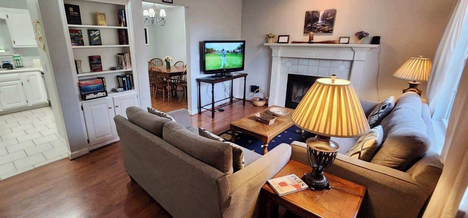 A living room with a sofa, a television, a fireplace, and a bookshelf.