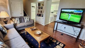 Un salon comprenant un canapé, une table basse, un téléviseur et une bibliothèque.