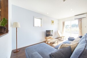 Uma sala de estar moderna com um sofá, TV e uma luminária de chão.