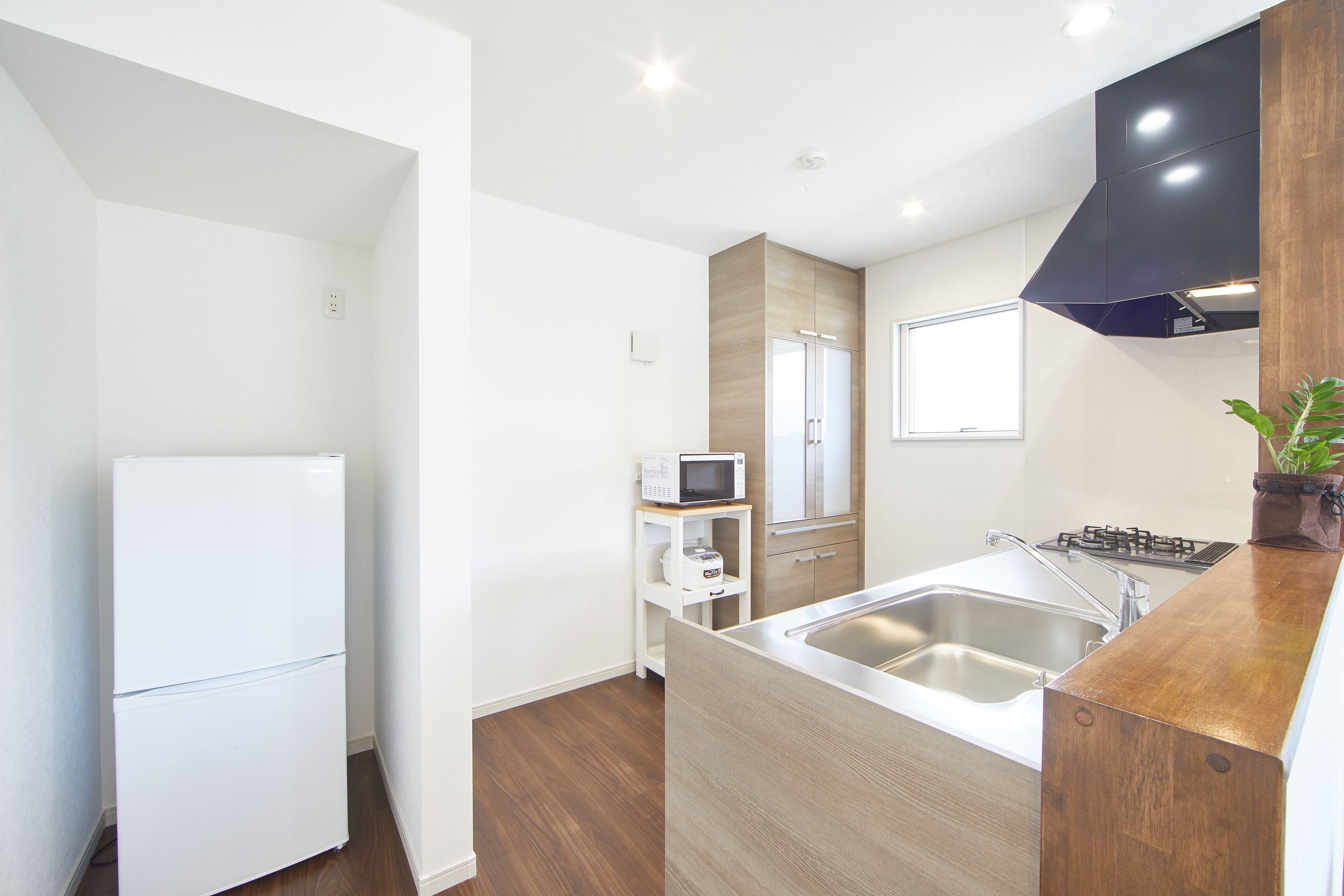 A modern kitchen with a refrigerator, microwave, sink, and wooden cabinets.