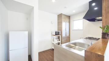 Una cucina moderna con frigorifero, forno a microonde, lavello e pensili in legno.