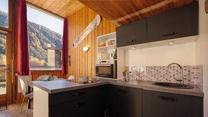 Una cocina moderna con techo de madera, un ventanal y vistas a la montaña.