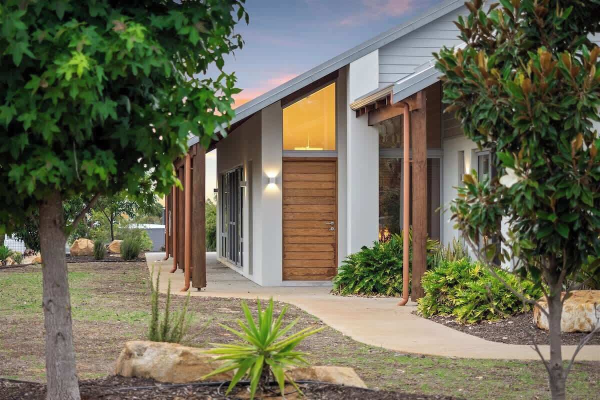 A modern house with a wooden front door, a covered porch, and a landscaped garden.