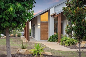 A modern house with a wooden front door, a covered porch, and a landscaped garden.