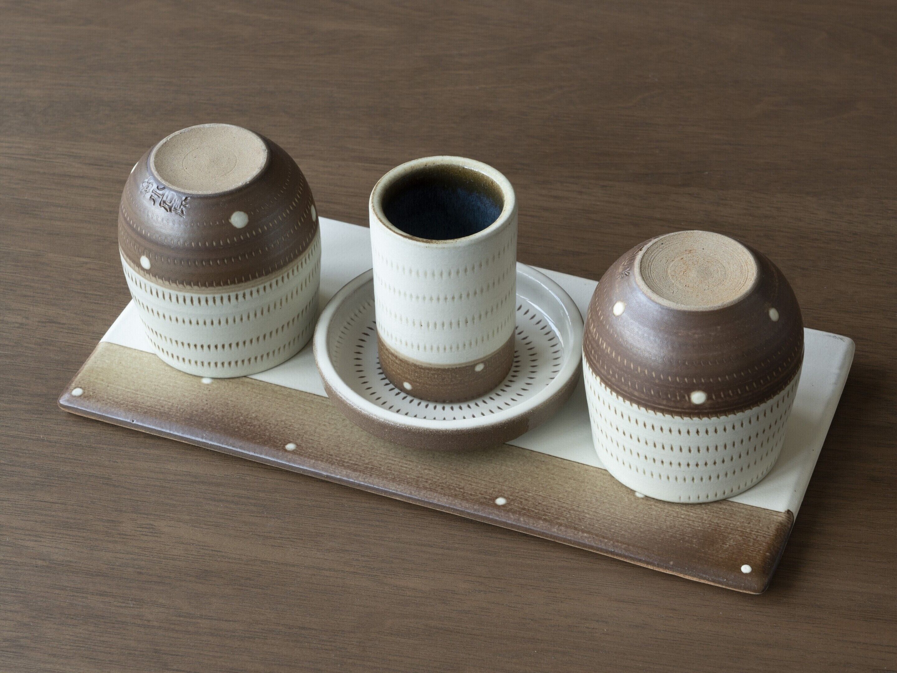 Three ceramic cups on a wooden tray.