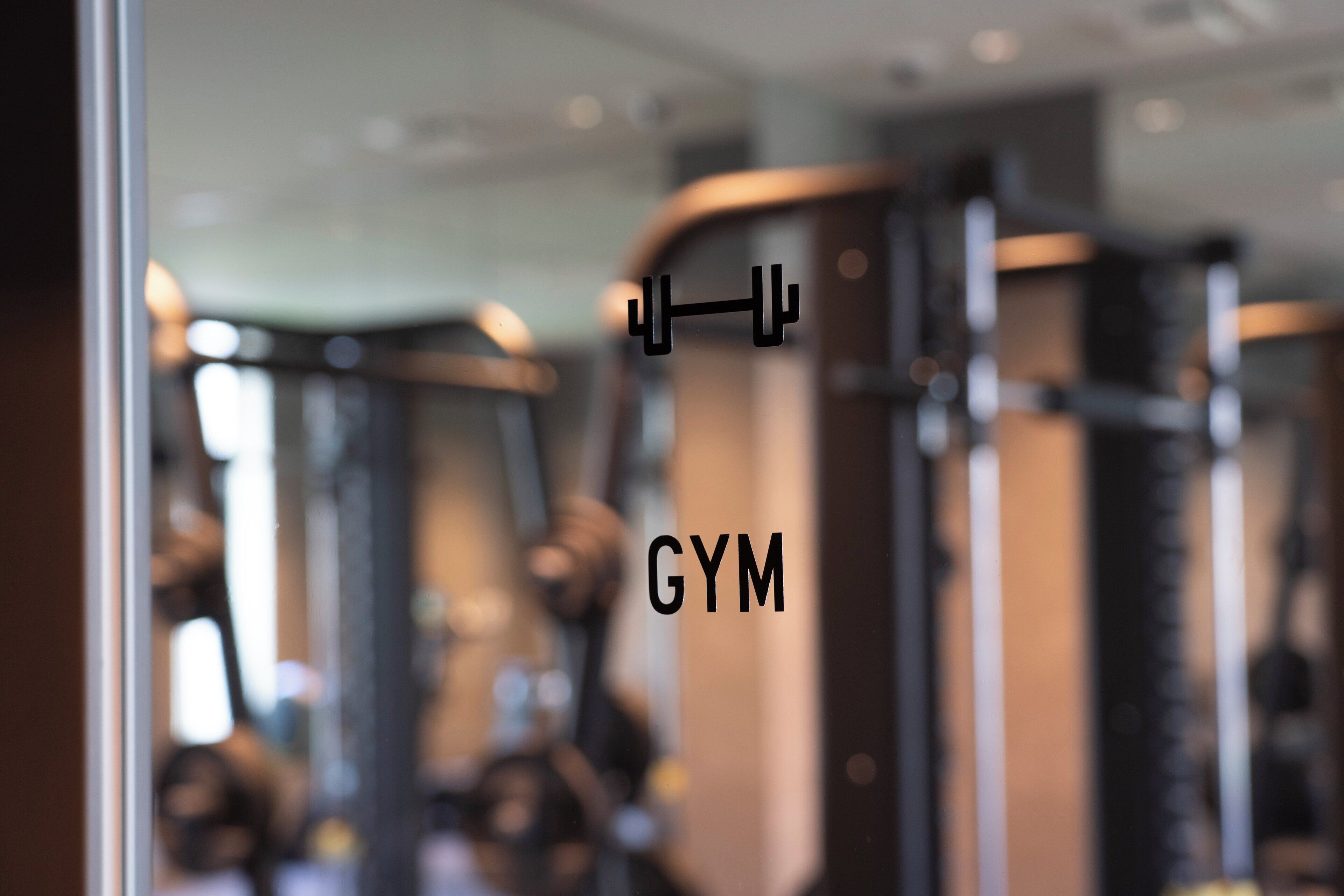 A blurred gym interior with exercise equipment and a weight rack.