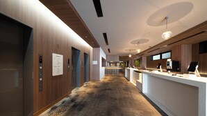 Un vestíbulo moderno de hotel con una recepción, ascensores y un largo pasillo.