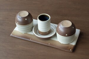 Un juego de tres tazas y platillos de cerámica sobre una bandeja de madera.