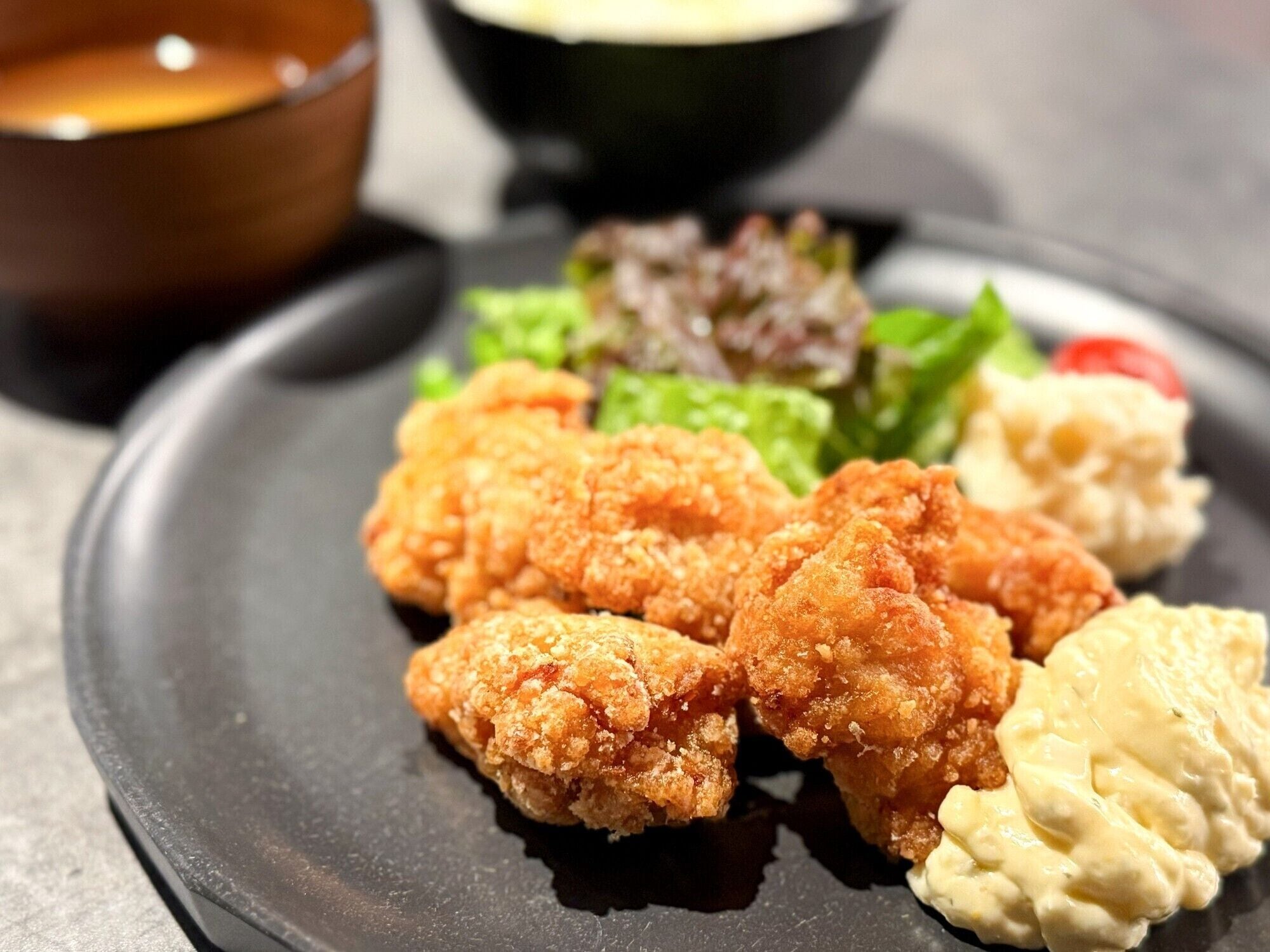 A plate with breaded chicken pieces, a side salad, and a creamy sauce.
