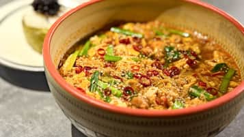 Un bol de soupe de nouilles asiatique, garnie de légumes et de viande, et servie dans un bol en fibres tressées.