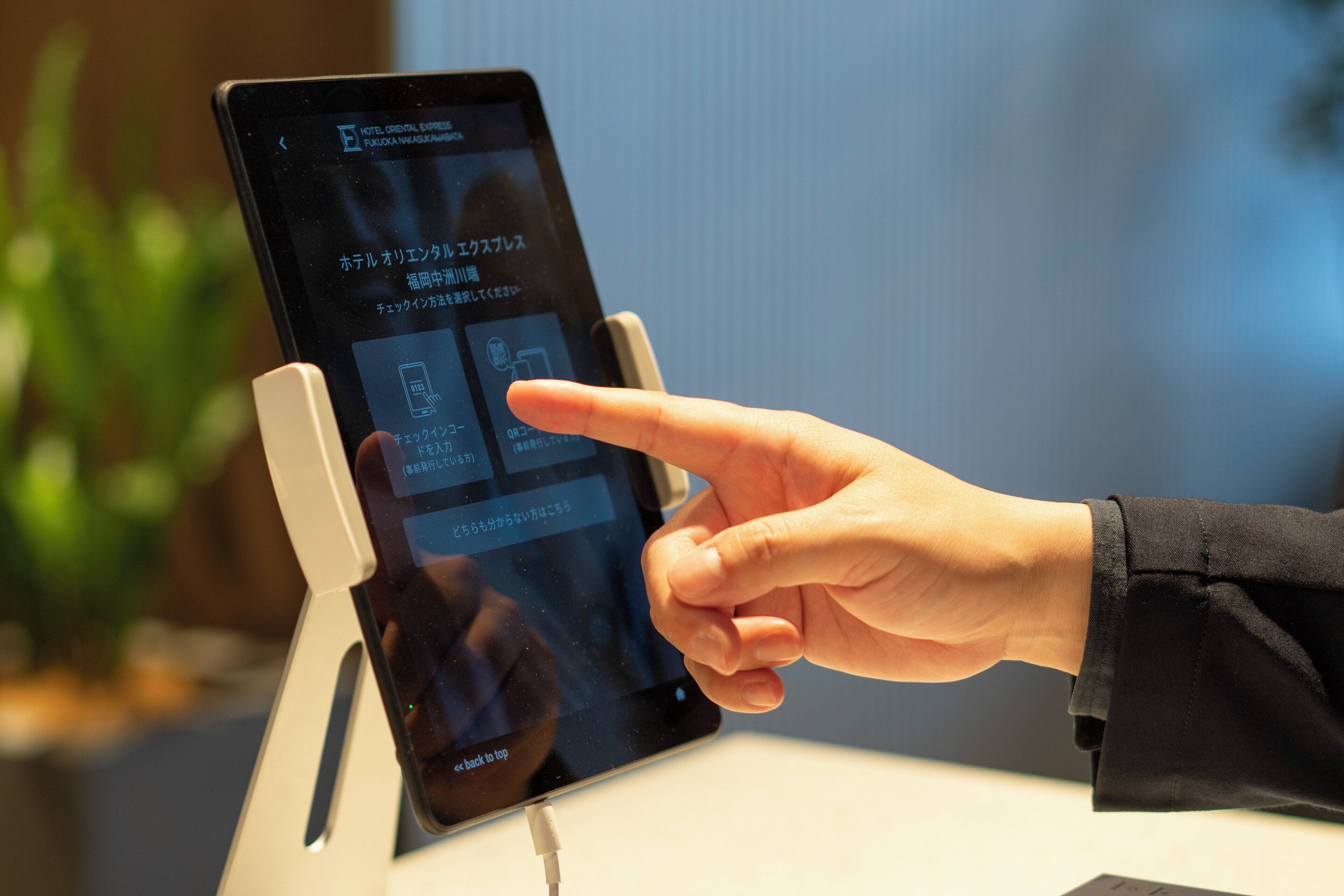 Een hand die een tablet bedient waarop informatie over een hotel wordt weergegeven.