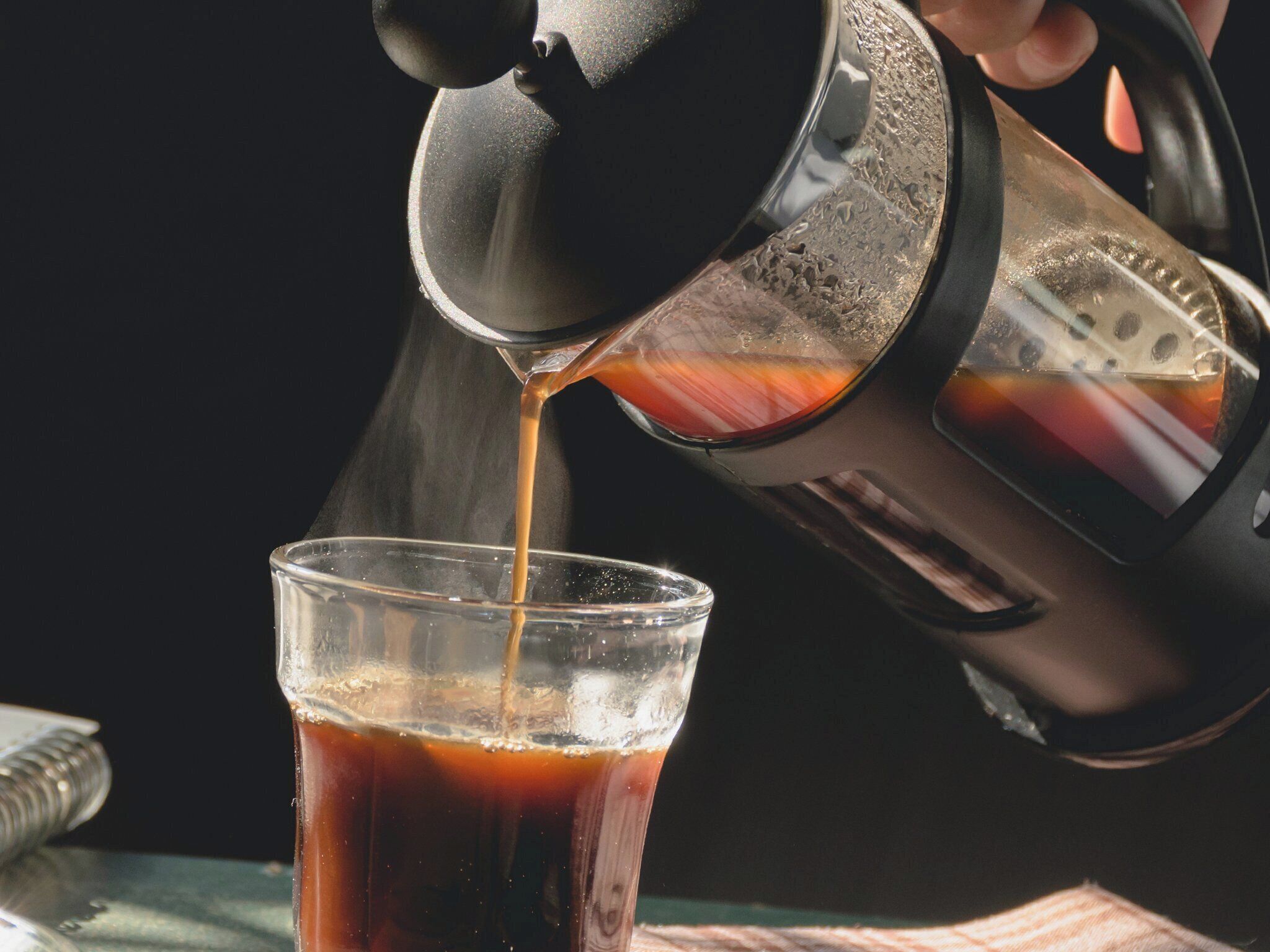 Una cafetera sirviendo café en un vaso.