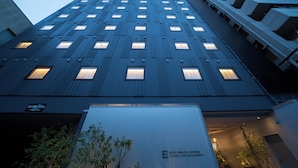 Un moderno edificio de hotel con un diseño vertical llamativo, múltiples ventanas y un cartel que indica que es el Fukuoka Nakasu Awata Hotel.