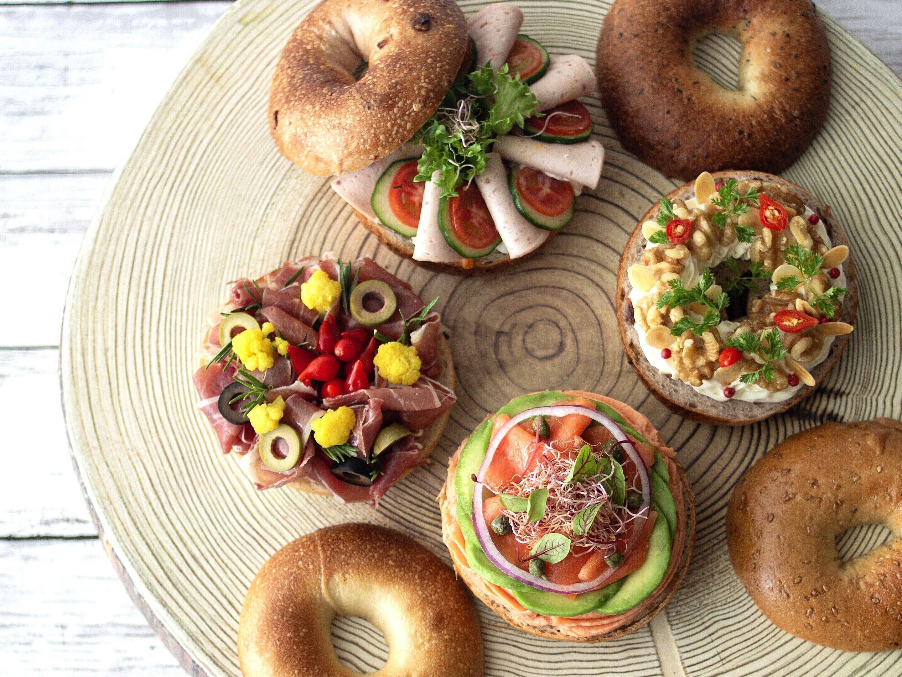 Verschiedene Bagels mit unterschiedlichen Belägen, darunter Frischkäse, Gemüse und Fleisch.
