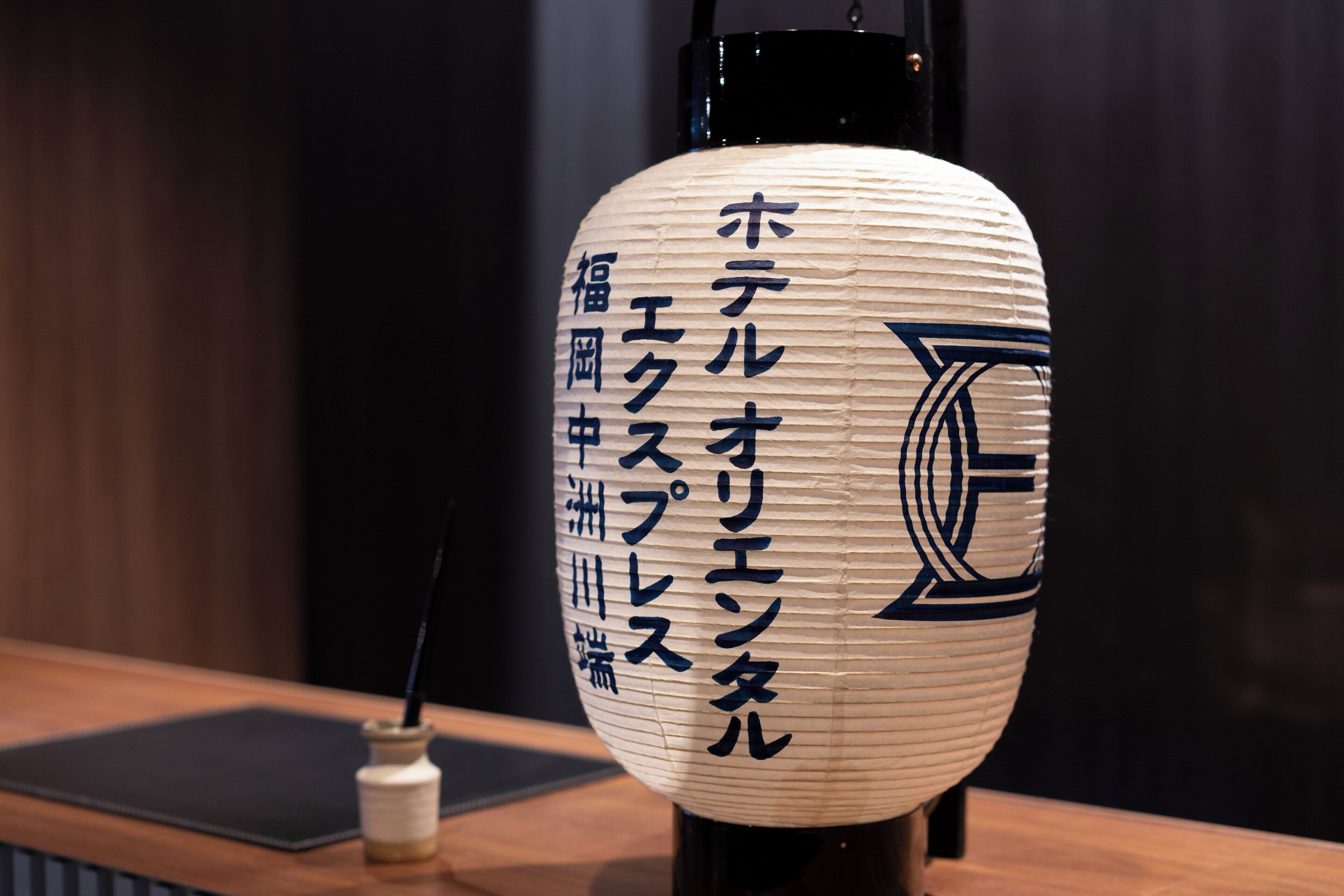 A traditional Japanese paper lantern with Japanese characters on it, placed on a wooden table.