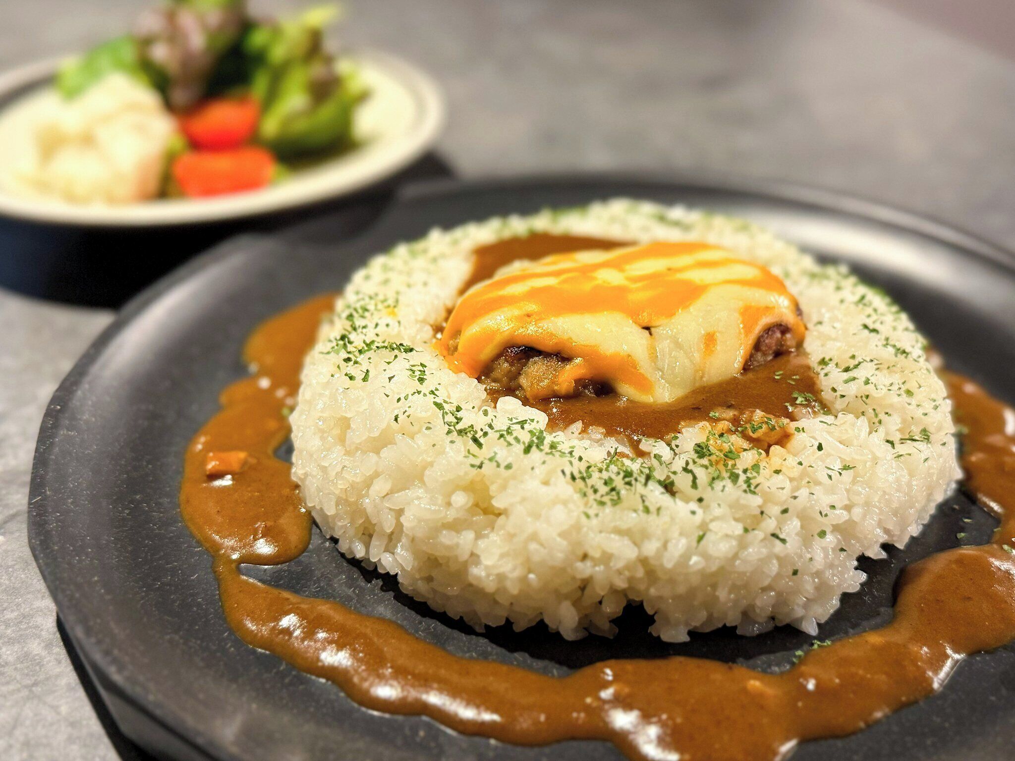 A plate of rice topped with a meat dish and sauce, garnished with herbs.