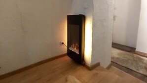 A cozy room with a fireplace, wooden flooring, and a white rug.