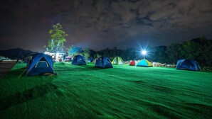 A row of tents on a grassy field at night with artificial lighting. - Ozone Tented Camp See the Star (Pak Chong)