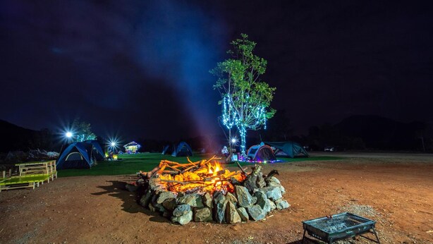 A campsite at night with tents, a campfire, and a tree decorated with lights. - Ozone Tented Camp See the Star (Pak Chong)