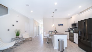 A modern kitchen with white cabinetry, stainless steel appliances, and a central island. - MO4393 Storey Lake Condo  5Beds 4Baths Private Pool and Free Waterpark (Kissimmee)