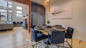 A modern dining area with a round table, dark chairs, and a decorative hanging light fixture.