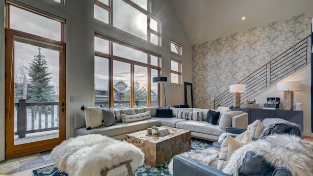 A spacious living room with a large window, a staircase, and a cozy seating area.