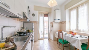 Una cocina moderna con estufa, pileta y comedor con sillas y mesa.