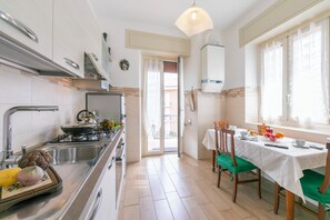 A modern kitchen with a stove, sink, and dining area with chairs and a table.