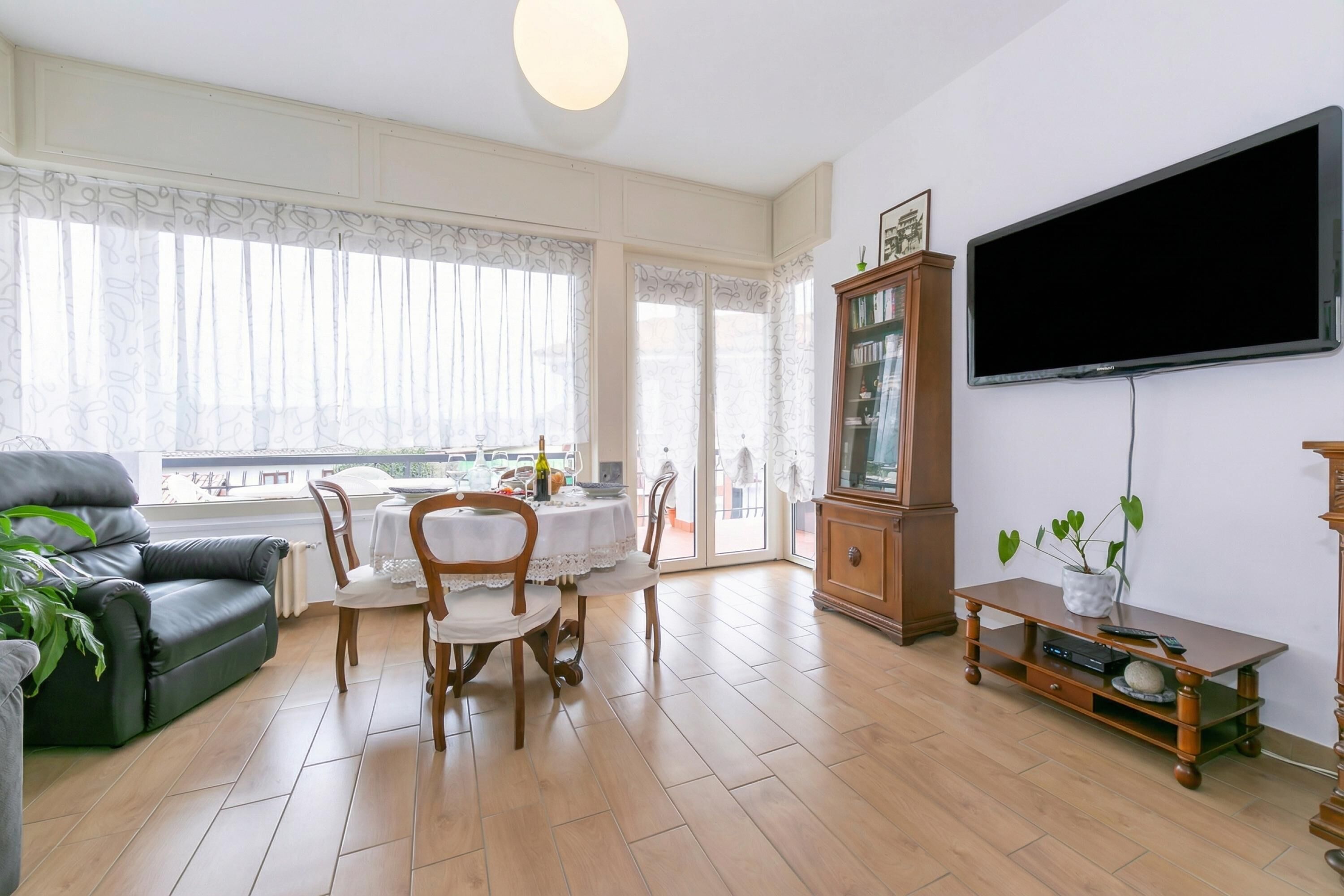A living room with a sofa, dining table, chairs, a TV, and a cabinet.