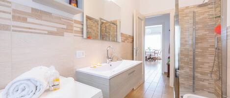 Een moderne badkamer met een wastafel, spiegel en douche.