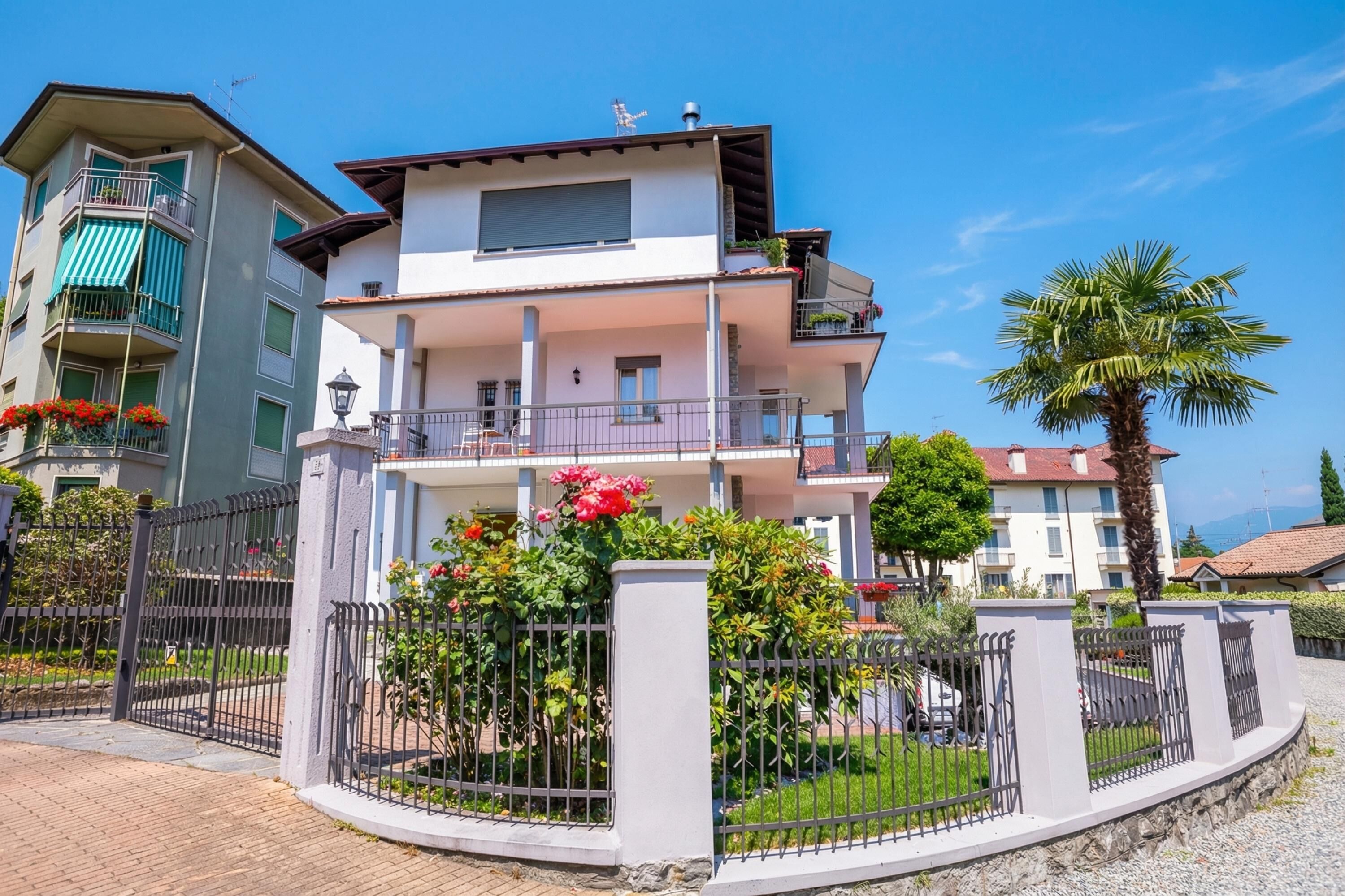 A multi-story residential building with balconies, a gated entrance, and a well-maintained garden.