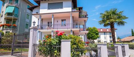 A multi-story residential building with balconies, a gated entrance, and a well-maintained garden.