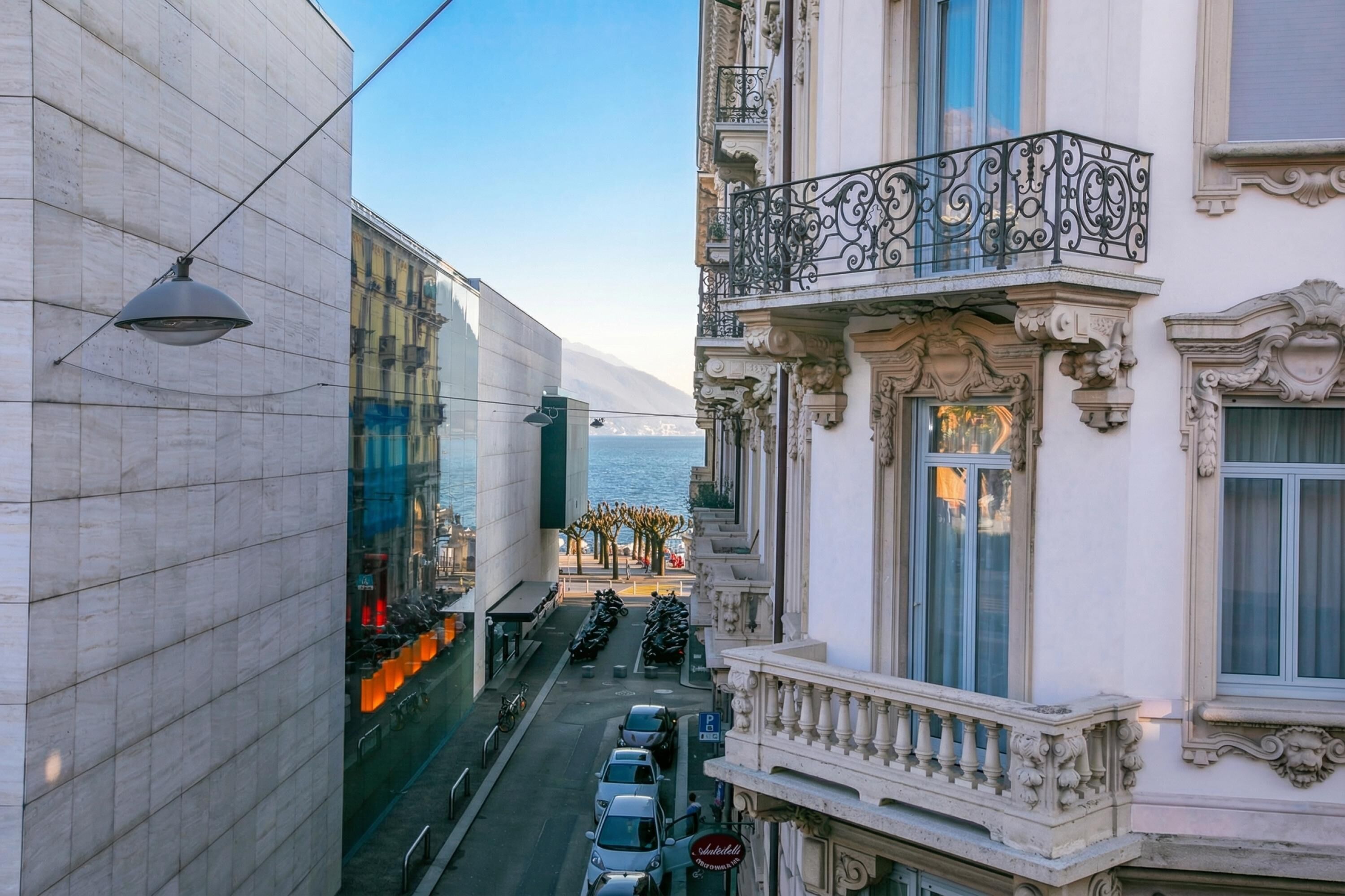 Vista de la calle con un edificio que presenta balcones ornamentales y vistas al mar.