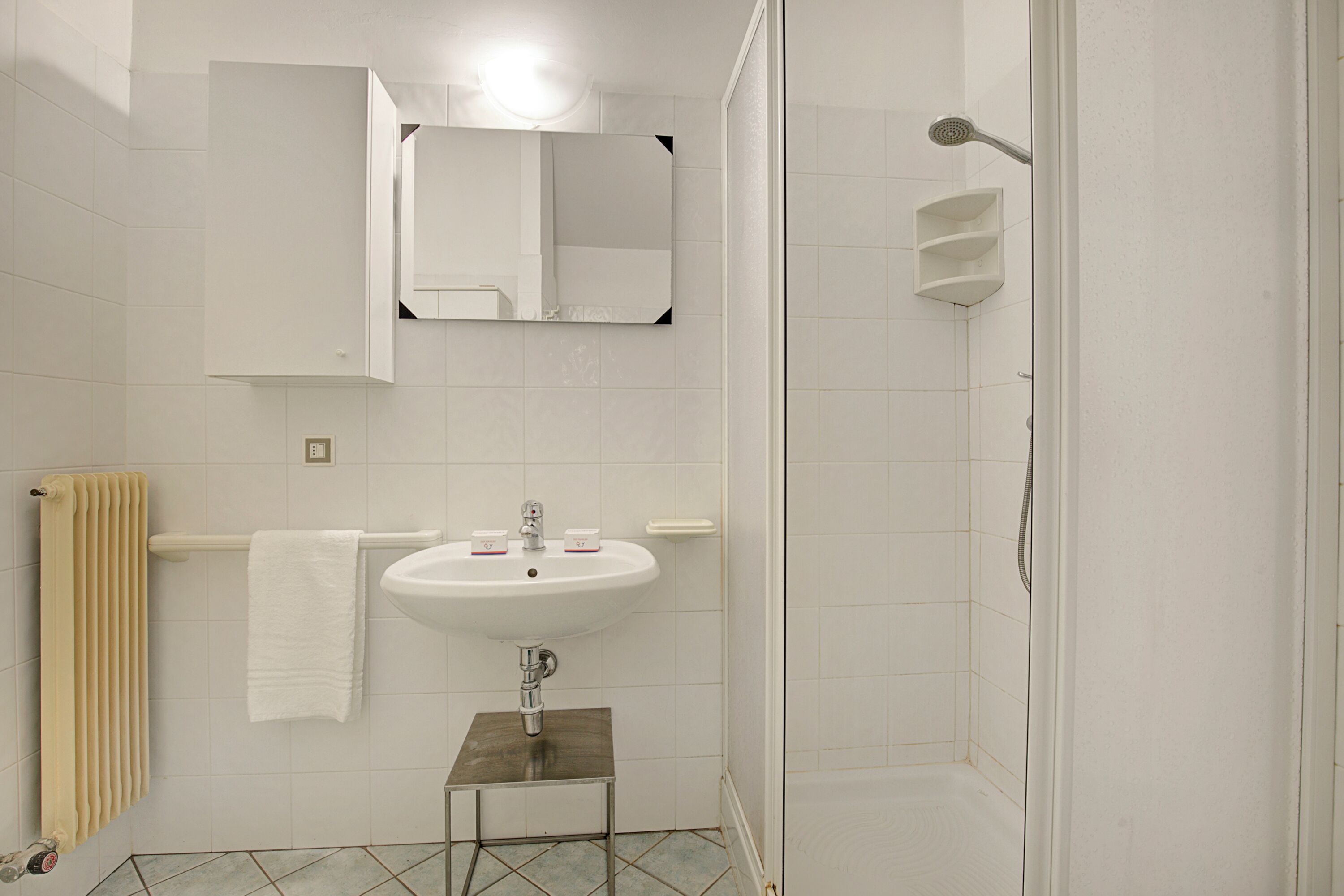 A bathroom with a sink, mirror, and shower.