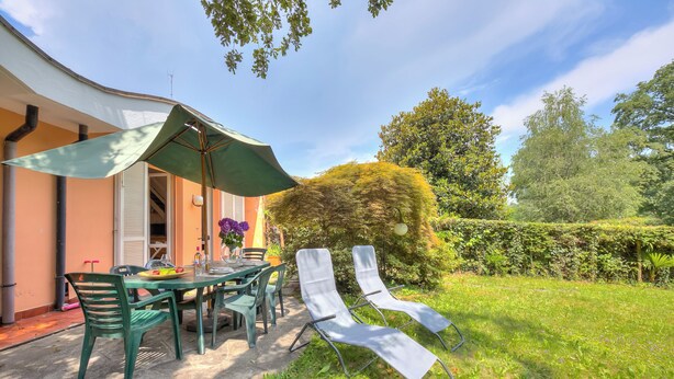 An outdoor patio with a table, chairs, and a green umbrella. - Riva del Caolino (Ispra)