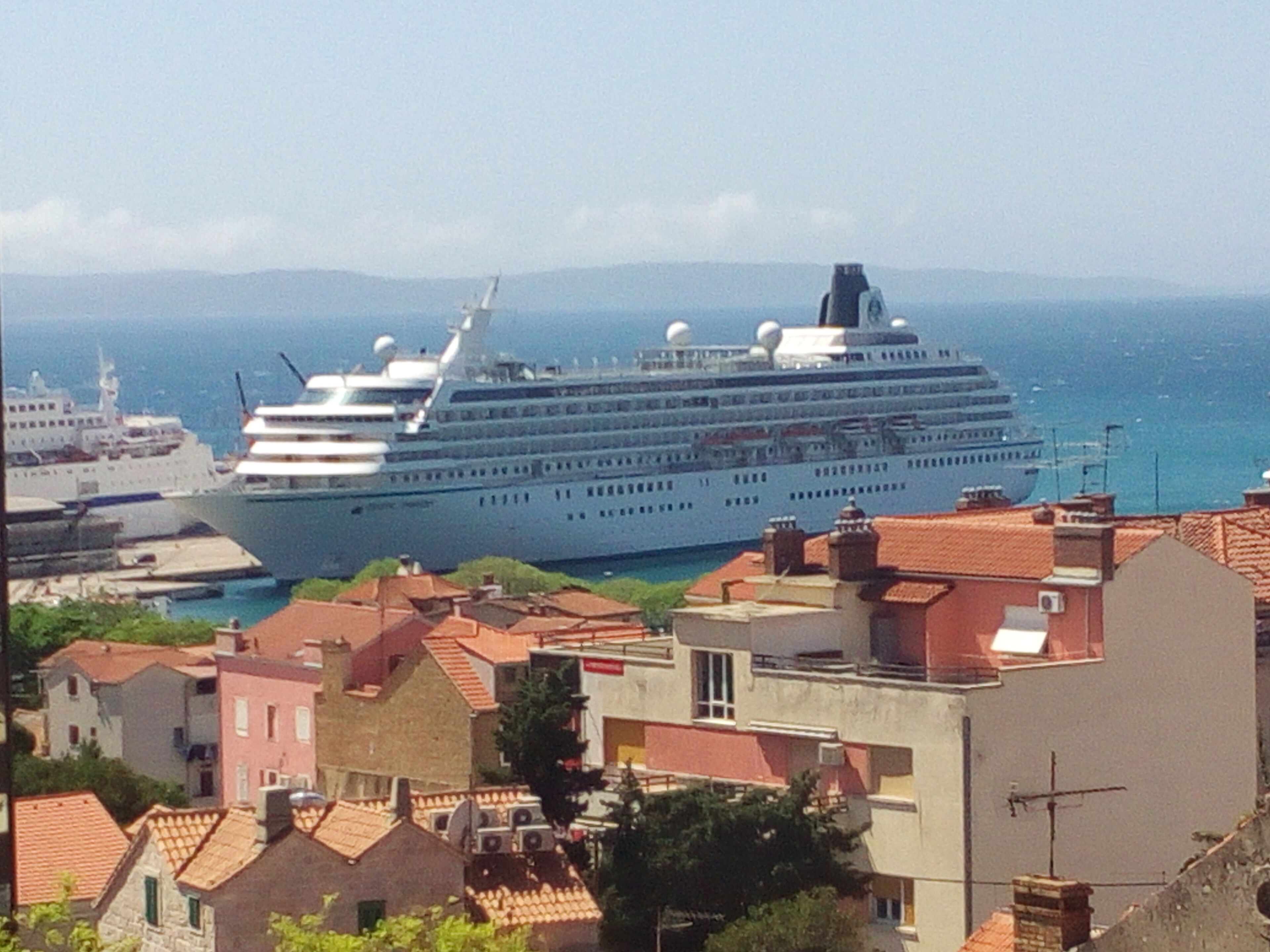 A large cruise ship docked at a port with buildings in the foreground.