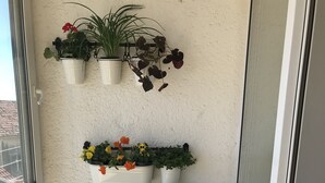 A white cabinet with three drawers and a shelf holding various potted plants. - Apartment City Walk (Split)